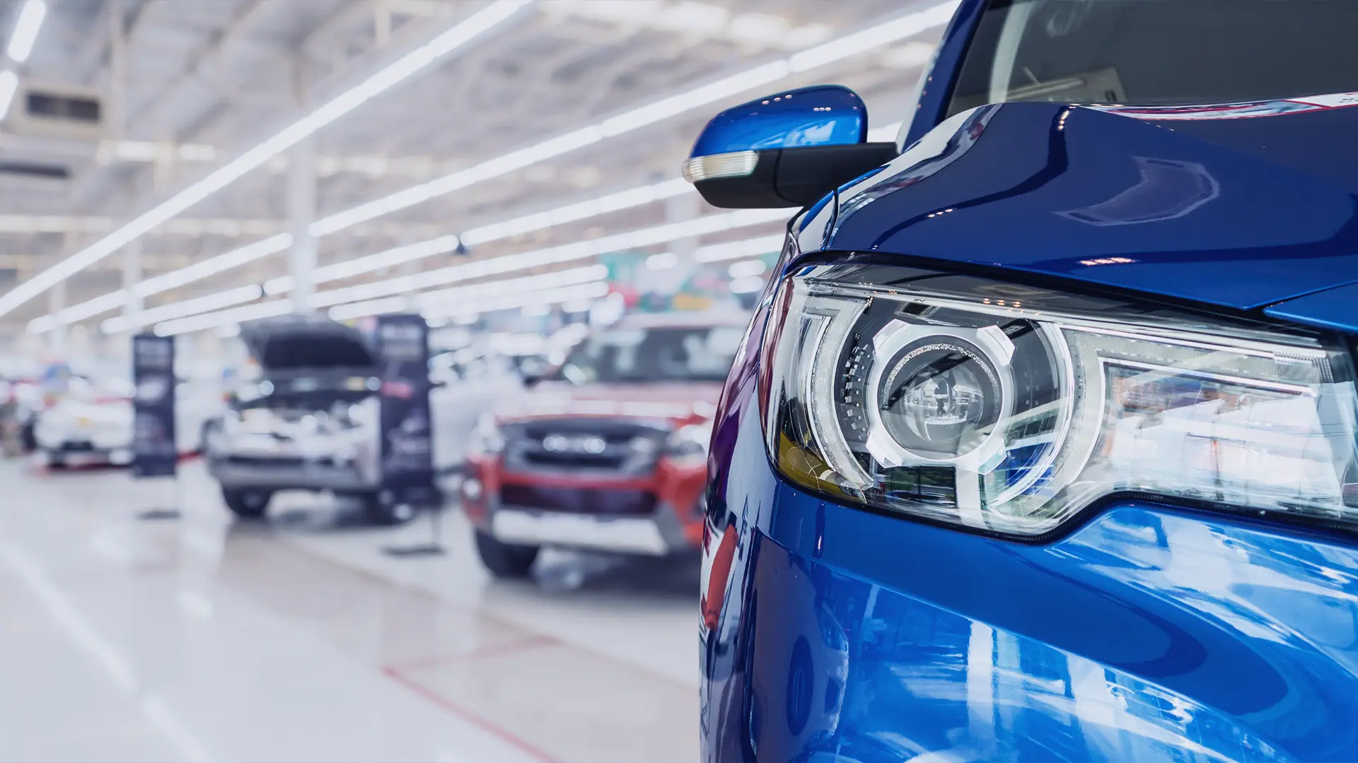 New vehicles in a production hall, a headlight in the foreground