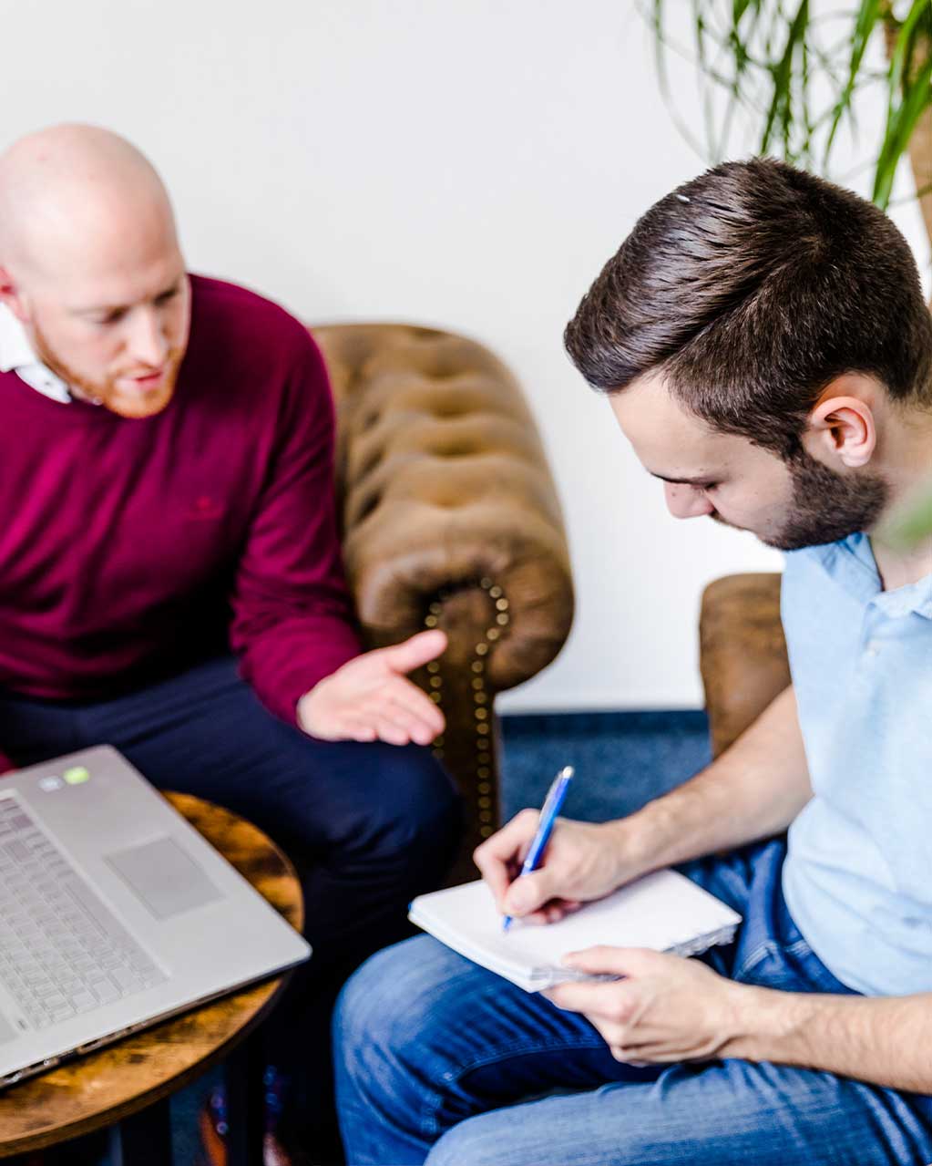 Two consultants in conversation, one taking notes